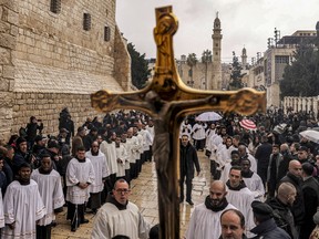 A crucifix is raised as deacons and other clergymen congregate for Christmas Eve celebrations outside the Church of the Nativity in Bethlehem in the occupied West Bank on December 24, 2023.