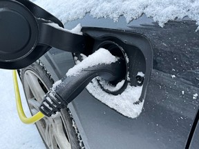 Close up of charging electric car in the winter with snow outside.