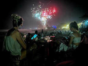 Fireworks illuminate the night sky as revelers celebrate New Year's Eve at the beach on Dec. 31, 2023 in the Kerobokan district on the resort island of Bali, Indonesia.