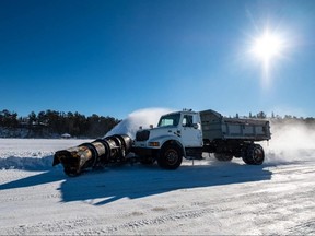 A vehicle plows a winter ice road.