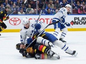 Leafs captain John Tavares lies on top of Canucks forward Teddy Blueger at Rogers Arena on Saturday.