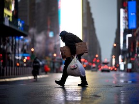 A homeless man carries cardboard as he crosses the almost deserted Times Square on April 13, 2020 in New York City.
