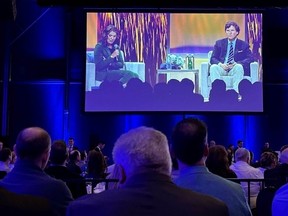 Alberta Premier Danielle Smith is shown onstage with Tucker Carlson