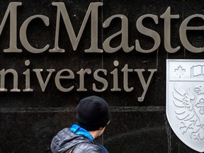 A pedestrian walks past signage for McMaster University on Toronto's Bloor Street West, Wednesday November 16, 2022.