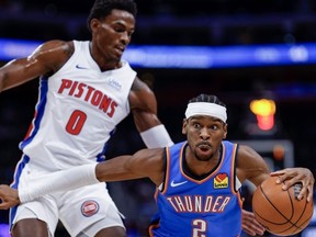 Shai Gilgeous-Alexander #2 of the Oklahoma City Thunder dribbles the ball against Jalen Duren #0 of the Detroit Pistons in the first quarter of a game at Little Caesars Arena on January 28, 2024 in Detroit, Michigan.