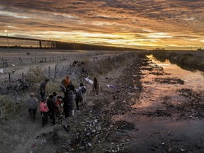 Seen from an aerial view, immigrants wait next to razor wire after crossing the Rio Grande into El Paso, Texas on February 01, 2024 from Ciudad Juarez, Mexico.