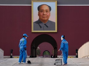 Two men clean the ground in front of the portrait of the late Communist Party leader Mao Zedong on April 29, 2020 in Beijing, China.