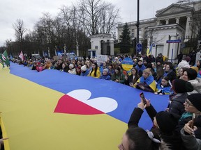Ukrainians and Poles march with a giant Ukrainian flag in protest of Russia's military aggression against Ukraine on the second anniversary of the war, in front of the Russian Embassy in Warsaw, Poland, Saturday Feb. 24, 2024.
