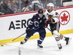 Winnipeg Jets' Mark Scheifele (55) and Chicago Blackhawks' Jaycob Megna (24) go for the loose puck during first period NHL action in Winnipeg on Thursday, January 11, 2024. The Jets activated Scheifele from injured reserve hours before their game Tuesday night at Pittsburgh.
