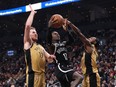 Brooklyn Nets' Dennis Schroder (centre) shoots between Toronto Raptors' Jakob Poeltl (left) and Immanuel Quickley in Toronto on Thursday, February 22, 2024.