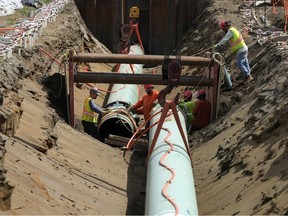 Workers lay pipe during construction of the Trans Mountain pipeline expansion on farmland in Abbotsford, B.C.