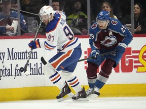 Connor McDavid collects an airborne puck as Nathan MacKinnon pursues during an Oilers-Avs game Sunday, Feb. 19, 2023, in Denver.