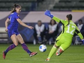U.S. forward Alex Morgan, left, shoots against Argentina goalkeeper Laurina Oliveros during the first half of a CONCACAF Gold Cup women's soccer tournament match Friday, Feb. 23, 2024, in Carson, Calif.