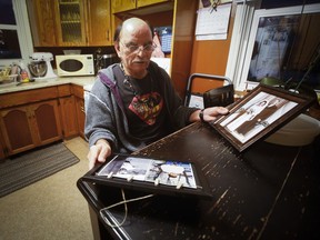 Eddy Ambrose, a Manitoba man who was switched at birth, looks at photos of the parents who raised him, James and Katherine Ambrose, and his biological parents, Laurette and Camille Beauvais, at his home in Winnipeg, Monday, Feb. 13, 2023. Ambrose and Richard Beauvais are to receive an apology from the Manitoba government.