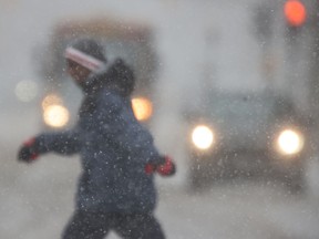 A person crosses in front of traffic during in a snow storm