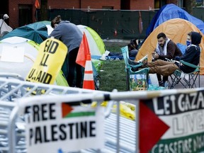 Activists sit outside their tents in an encampment at University Yard at George Washington University on April 29, 2024 in Washington, DC.
