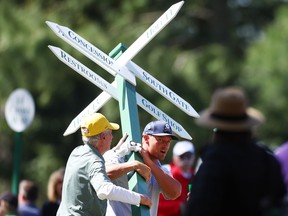 Bryson DeChambeau moves a sign while preparing to play his second shot on the 13th hole from the 14th fairway during the second round of the 2024 Masters Tournament at Augusta National Golf Club in Augusta, Ga., Friday, April 12, 2024.