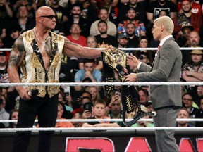 Dwayne 'The Rock' Johnson hands his People's Champion belt to new Undisputed WWE Universal Champion Cody Rhodes during the opening segment of Monday Night Raw in Philadlphia on Monday, April 8, 2024.