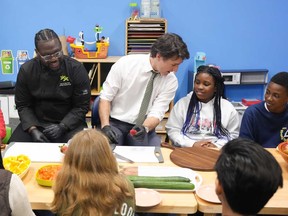 Prime Minister Justin Trudeau talks to ten year old Chakai as he cuts fruit next to chef Jason Simpson while preparing food for a lunch program at the Boys and Girls Club East Scarborough, in Toronto, Monday, April 1, 2024.