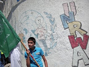 A Palestinian boy holds a Hamas flag as he protests against a UN Relief and Works Agency (UNRWA) funding gap, outside the UNRWA Gaza headquarters in Gaza City, in 2015.