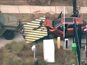 An image taken from aerial video shows a red vehicle stopped by a barrier at the front gate of the Federal Bureau of Investigation Atlanta division, Monday, April 1, 2024, in Chamblee, Ga.