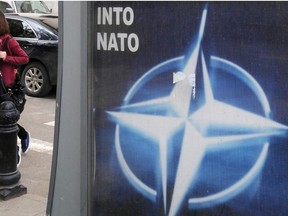 Georgian young women walk past a poster bearing the NATO logo in Tbilisi on May 6, 2009.