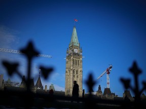 A person walks past the Peace Tower on Parliament Hill in Ottawa on Tuesday, Feb. 13, 2024.