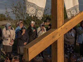 Orthodox devotees stand next to baskets of traditional Easter delights as they wait upon a Ukrainian priest to be blessed on Orthodox Easter in the village of Krasne, Chernigiv region, on May 5, 2024, amid the Russian invasion of Ukraine.