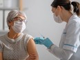 A doctor gives a senior woman a shot of a vaccine.