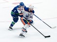Edmonton Oilers' Leon Draisaitl (29) skates with the puck while being watched by Vancouver Canucks' Conor Garland (8) during the third period in Game 1 of an NHL hockey Stanley Cup second-round playoff series, in Vancouver, on Wednesday, May 8, 2024.