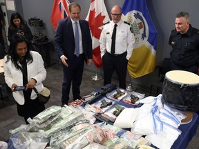 Justice Minister Matt Wiebe (centre left) and Insp. Elton Hall with seized money and drugs