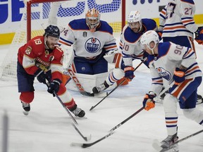 Edmonton Oilers' Corey Perry (90) moves the puck away from Florida Panthers' Matthew Tkachuk (19) during the first period of Game 5 of the NHL hockey Stanley Cup Finals, Tuesday, June 18, 2024, in Sunrise, Fla.