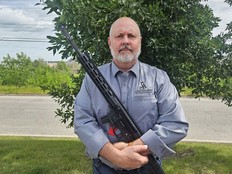J.R. Cox poses with his Calgary-based firm's gun, a semi-automatic nine-millimetre rifle, which was classified as a prohibited firearm by the RCMP.